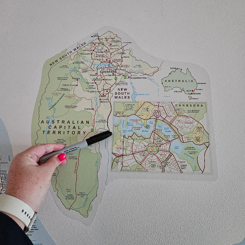 Hand holding a marker over a map of Australia on a white surface