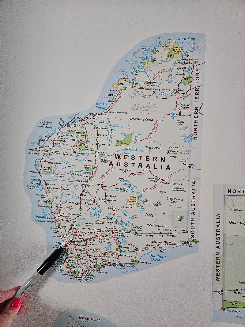 Map of Western Australia with a hand holding a pen pointing at a location.