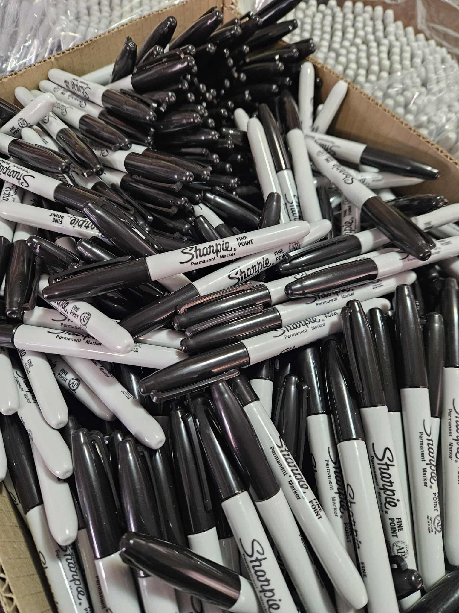 Box filled with Sharpie markers in black and white.