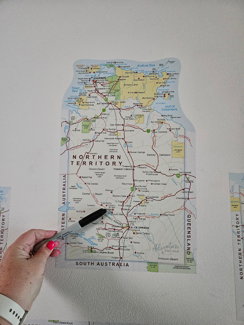 Map of Australia with a hand holding a marker over Queensland