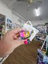 Hand holding Motus Mini CMY Cube with drawstring pouch inside gift shop, colourful fidget toy gift Adventure Awaits