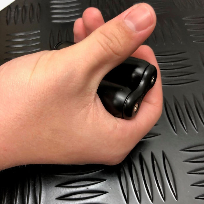 hand holding a black dual roller sensory fidget tool against a textured dark surface