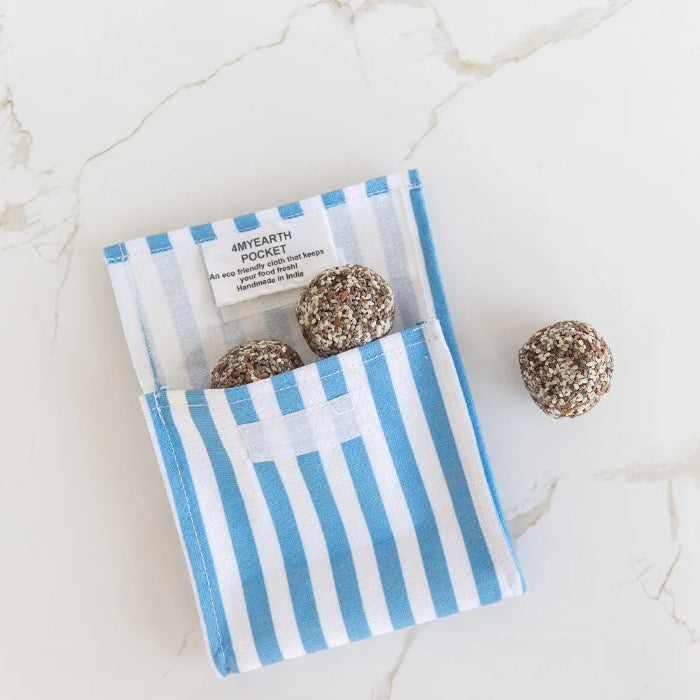 Reusable snack pouch with blue and white stripes holding energy balls, eco friendly food storage for snacks at home or travel Adventure Awaits