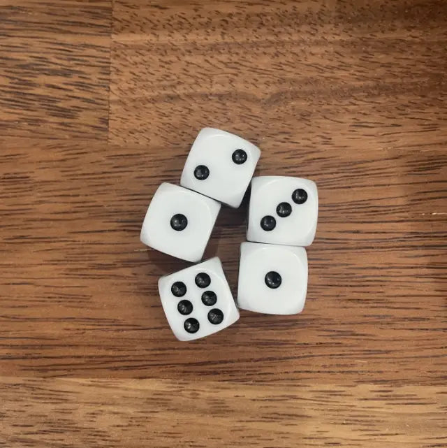 Five white dice with black dots scattered on a wooden tabletop — Adventure Awaits