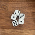 Five white dice with black dots scattered on a wooden tabletop — Adventure Awaits