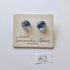Pair of stud earrings on a glass by Samantha Abbott Australia card with a white background.