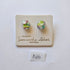 Pair of colorful glass earrings on a branded card with a white background