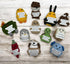 collection of handmade crochet emotional support plush toys with humorous quote signs arranged on a wooden background