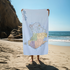 Person holding a towel with a map design on a beach