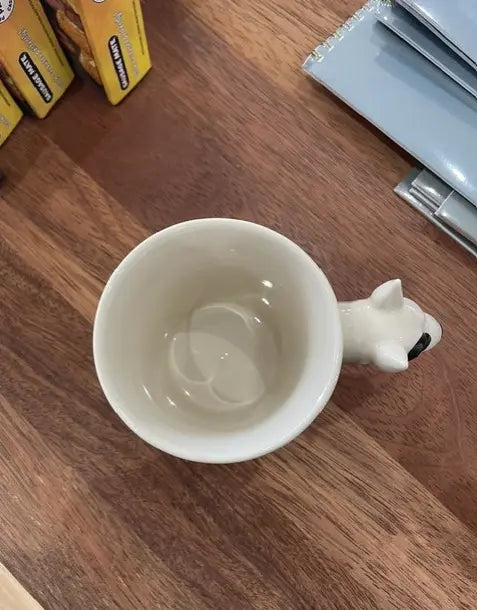 Top view of cream bull terrier mug with sculpted dog head handle on a wooden counter — Adventure Awaits