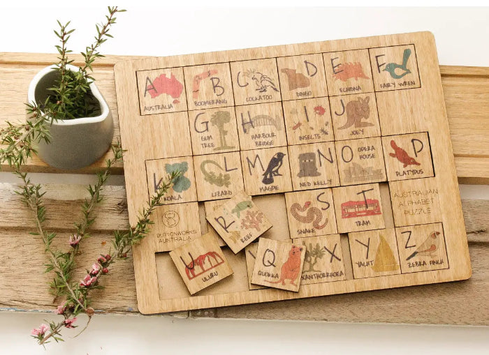 Australian alphabet timber puzzle with removable letter tiles, native animals and landmarks on a wooden table — Adventure Awaits