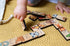 Child playing with Australian Heads & Tails timber animal game pieces on a knitted mat — Adventure Awaits