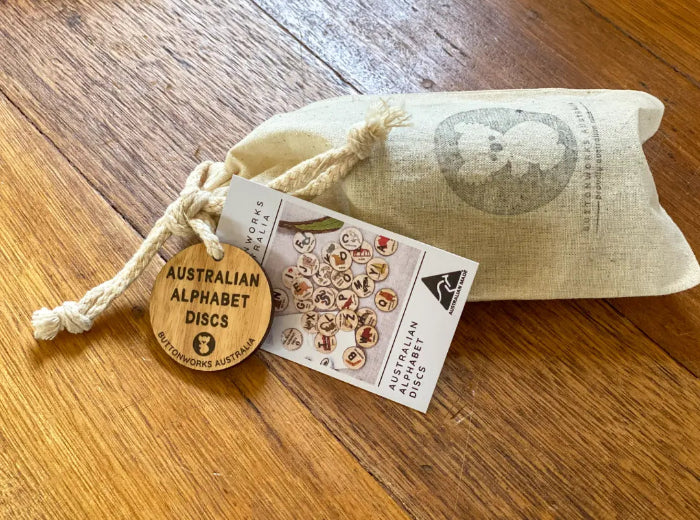 Australian alphabet timber discs packed in a cotton drawstring bag with product tag — Adventure Awaits