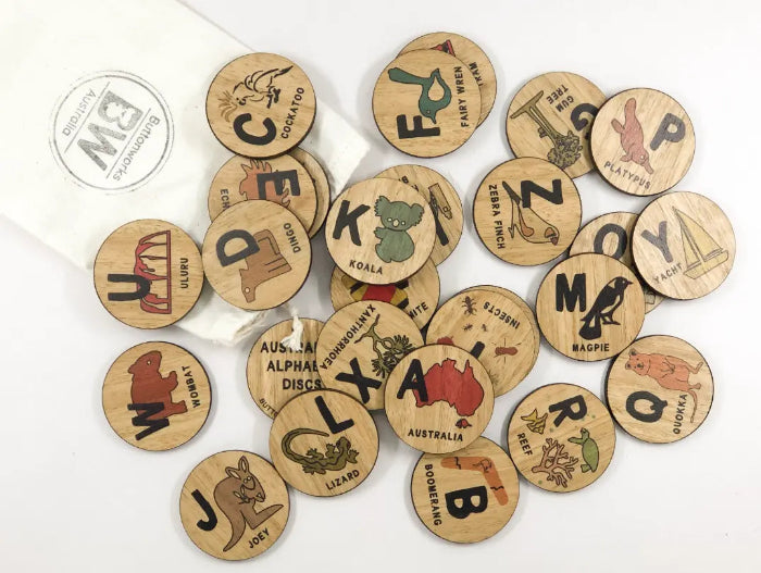 Australian alphabet timber discs scattered with native animals, landmarks and letter illustrations — Adventure Awaits
