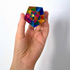 Hand holding a compact CMY Cube The Motus with vivid rainbow geometric reflections, Adventure Awaits