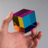 Hand holding a CMY Cube with vivid blue, yellow, magenta and orange transparent panels, Adventure Awaits