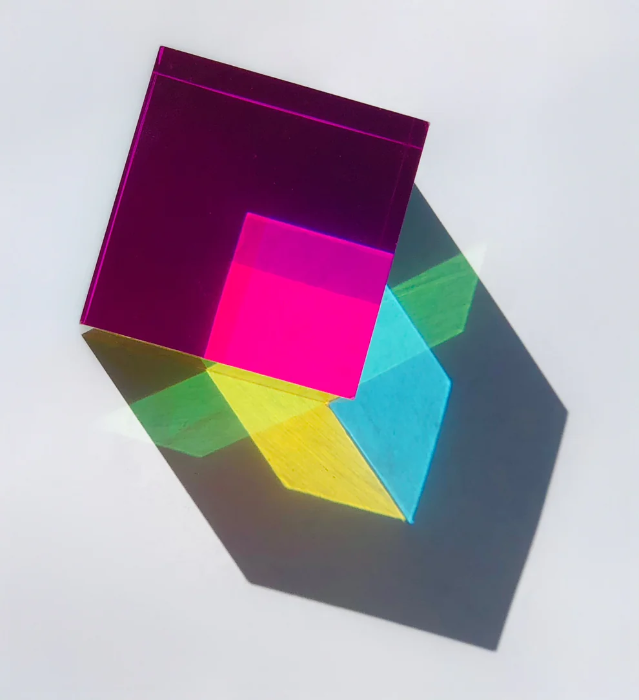 CMY Cube casting overlapping magenta, yellow, green and blue shadows in sunlight, Adventure Awaits