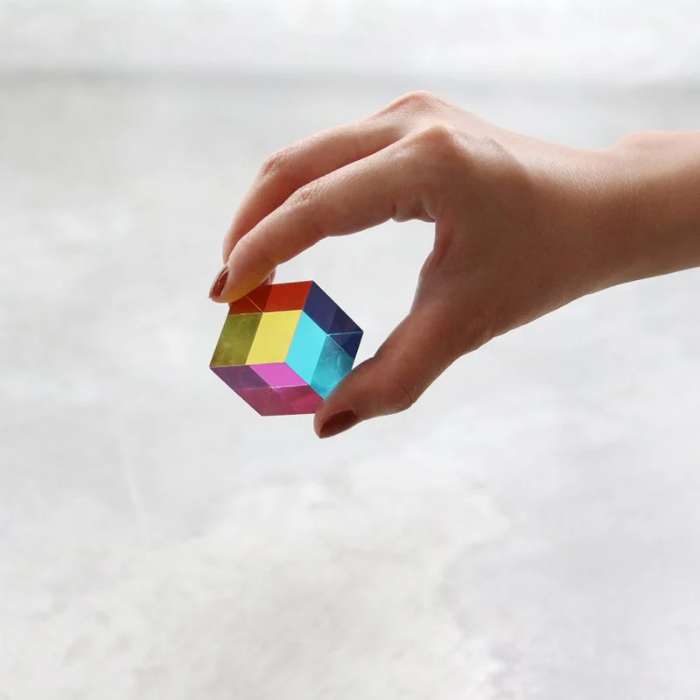Hand holding a mini CMY Cube with vivid transparent rainbow panels, Adventure Awaits