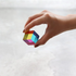 Hand holding a mini CMY Cube with vivid transparent rainbow panels, Adventure Awaits