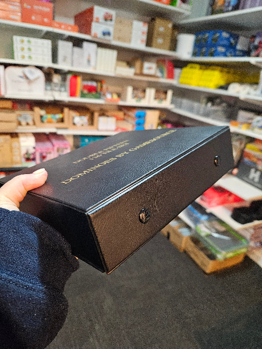 Hand holding the black Gamesource Double Fifteen domino storage case, showing its slim side profile — Adventure Awaits