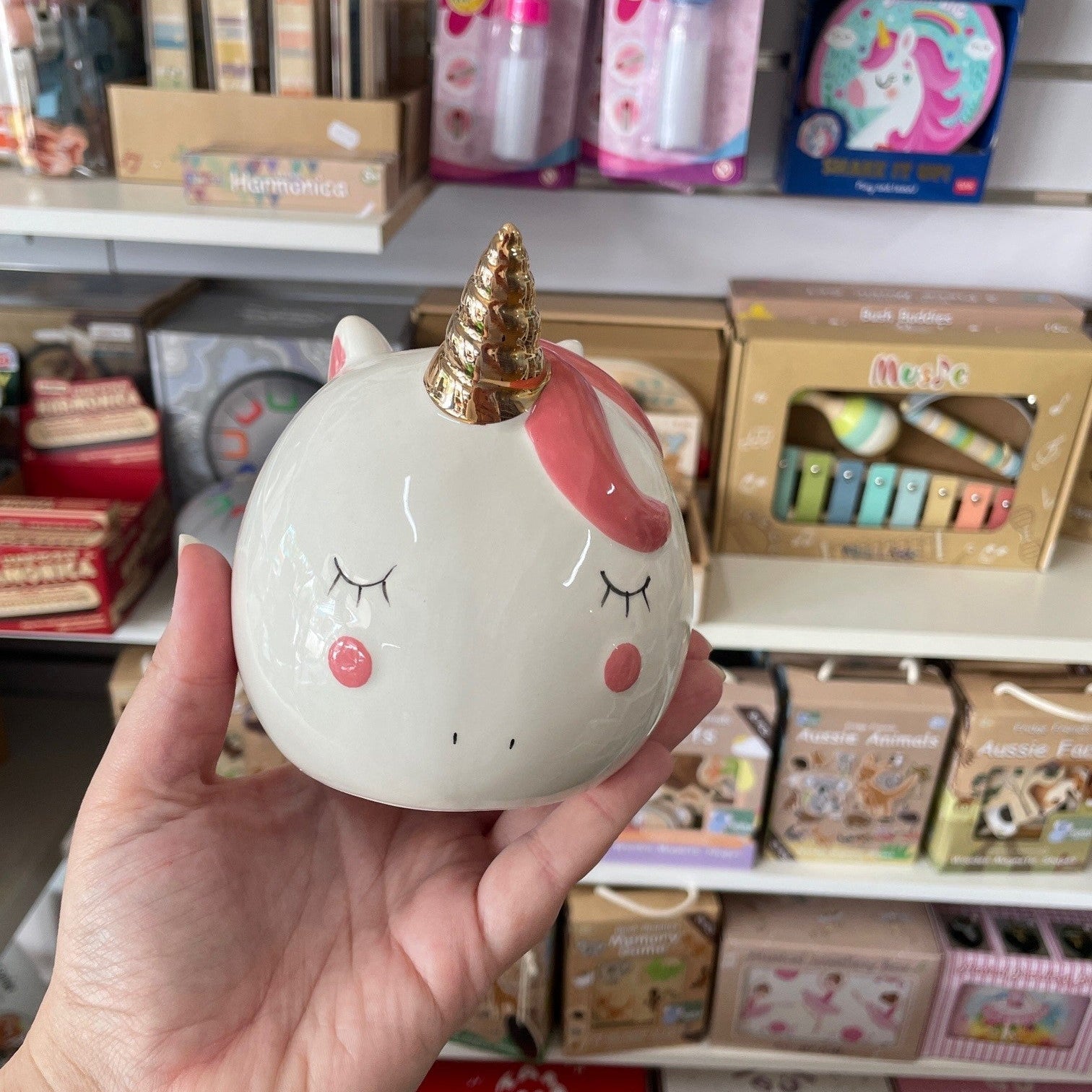 A white unicorn money box in a hand
