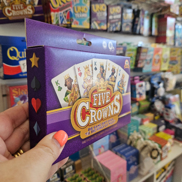 Five Crowns card game pack held in store, purple box with king cards Adventure Awaits
