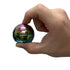 Oil slick gyroscope fidget shown pinched between thumb and forefinger against white background