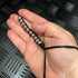 Hand caterpillar fidget in black with strap around wrist and beads in palm of hand