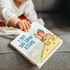 Child reaching for I Got You Some Kisses picture book on couch — Adventure Awaits