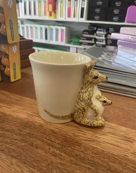 Cream kangaroo mug with sculpted kangaroo and joey handle on a wooden counter — Adventure Awaits