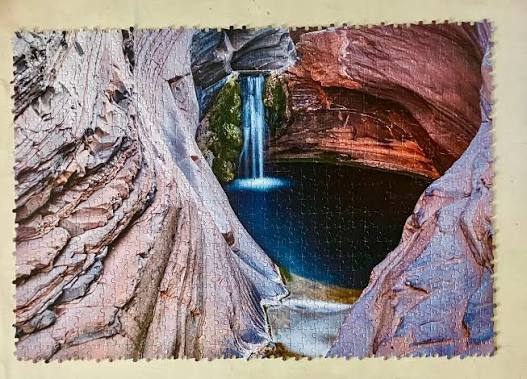 Completed Australian Geographic Karijini National Park jigsaw puzzle with waterfall gorge scene — Adventure Awaits