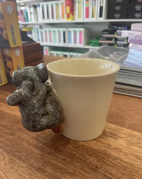 Cream koala mug viewed from behind with sculpted koala and joey handle on a wooden counter — Adventure Awaits