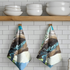 Two patterned towels hanging on a wooden shelf with white bowls.