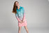 Girl smiling in an aqua and pink long-sleeve UPF50+ fishing dress against a plain backdrop — Adventure Awaits
