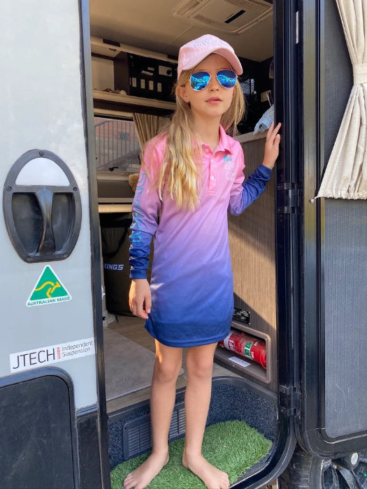 Girl in a pink, purple and blue UPF50+ fishing dress with cap and sunglasses at a caravan — Adventure Awaits