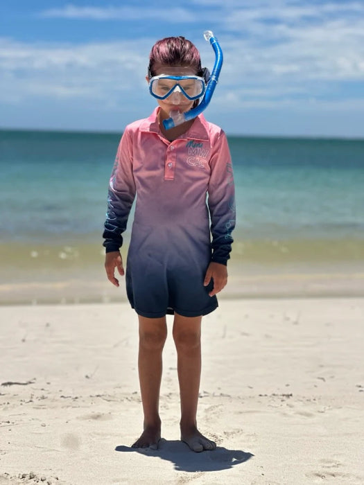 Child wearing a pink and navy long-sleeve swim top with snorkel mask while standing on a beach — Adventure Awaits