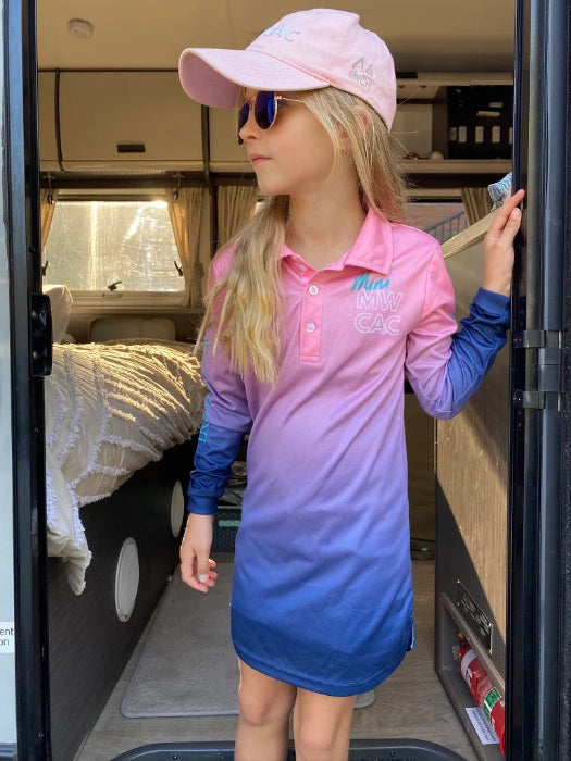 Girl wearing a pink, purple and blue UPF50+ fishing dress at a caravan doorway — Adventure Awaits