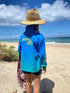 Child at the beach in a blue and aqua long-sleeve fishing shirt and wide-brim hat — Adventure Awaits