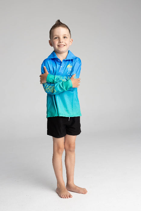 Boy smiling in a blue and aqua long-sleeve fishing shirt with black shorts — Adventure Awaits