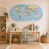 A large oval world map wall decal is displayed in a child's bedroom above a light wood desk with a mint green chair, books, and toys.