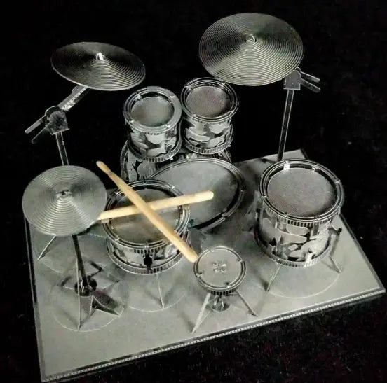Completed Metal Earth silver steel drum set model viewed from above with drumsticks across the drums, Adventure Awaits