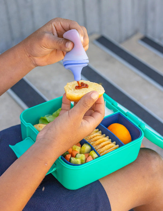 Silicone sauce bottle with lunch box containing food