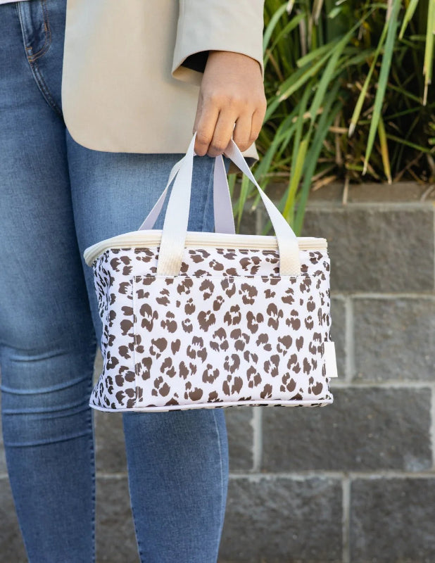 Woman carrying a white insulated lunch bag with brown leopard print and short handles — Adventure Awaits