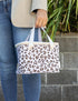 Woman carrying a white insulated lunch bag with brown leopard print and short handles — Adventure Awaits