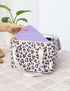 Hand placing a purple lunchbox into a white leopard print insulated lunch bag — Adventure Awaits
