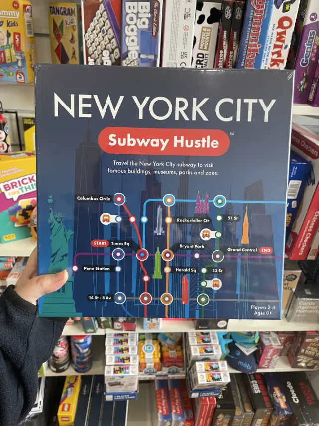 Hand holding New York City Subway Hustle board game in shop games aisle — Adventure Awaits