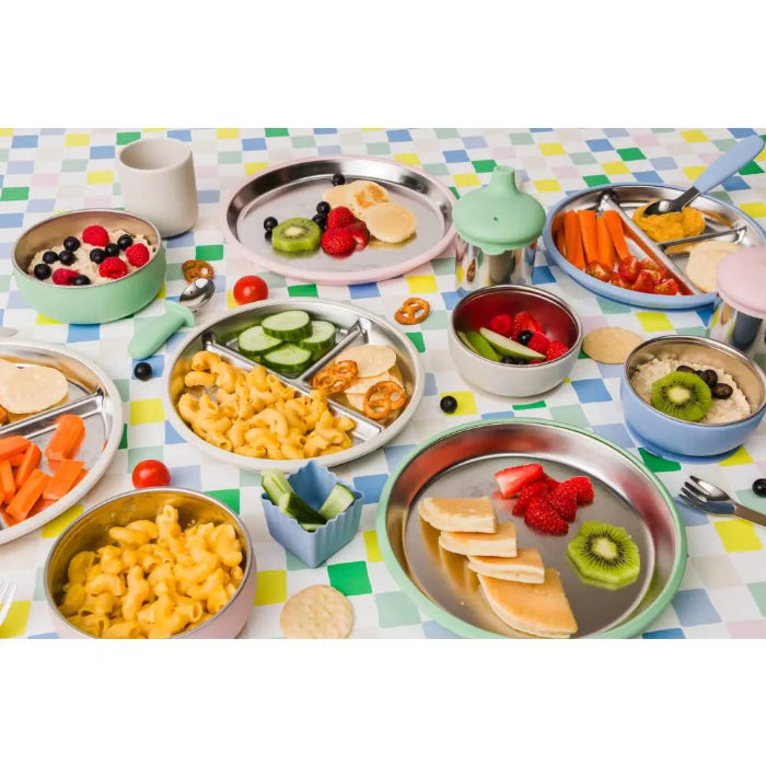 Colourful kids mealtime spread with stainless steel plates, bowls, cups and healthy snacks, Adventure Awaits