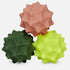 Three textured, spiky massage balls in dusty pink, dark green, and lime green, arranged together on a light gray background.