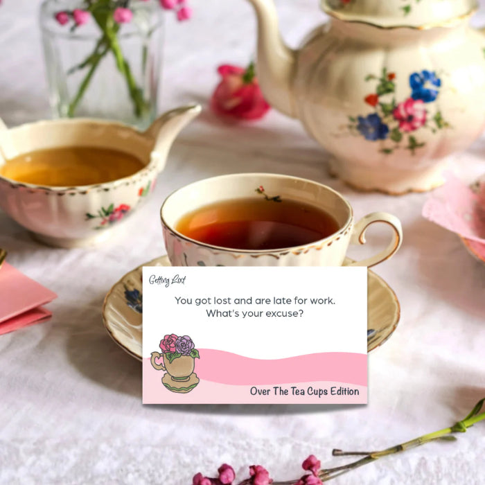 Vintage tea cup and card from Getting Lost Over The Tea Cups Edition on a floral tea table — Adventure Awaits