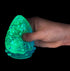 Hand squeezing green glow in the dark glitter drop squishy toy against black background — Adventure Awaits